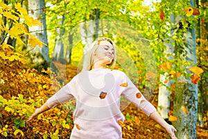 Girl throwing leaves up in air in autumn park