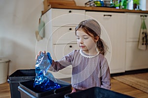 Girl throwing plastic bottles into recycling bin. Daughter sorting the waste according to material into bins.