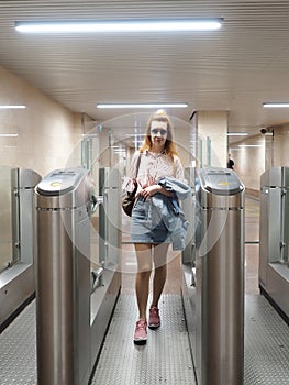 A girl with a ticket goes through the turnstile at the railway station