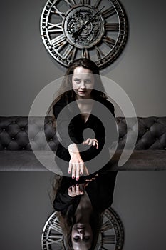 Girl and time. Beautiful young girl posing against the background of a wall clock photo