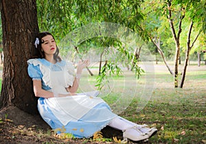 Girl tired of reading boring book sitting under a tree