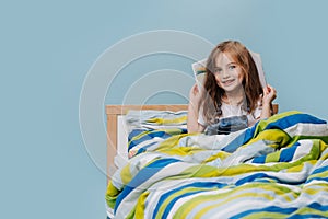 Girl Toddler plays with a book in bed