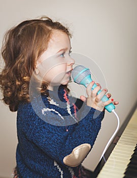 Girl toddler, piano and toy microphone