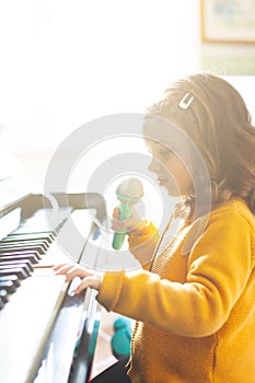 Girl toddler plays with piano and toy microphone