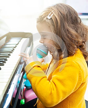 Girl toddler plays with piano and toy microphone