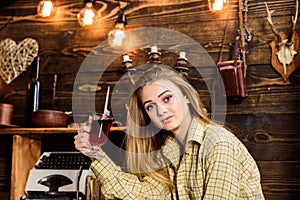 Girl tomboy relax with glass with mulled wine in house of gamekeeper. Girl in casual outfit sits in wooden vintage