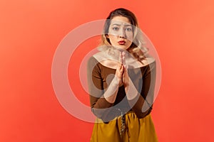 Girl took hands together and pray for hapiness. Looking at the camera