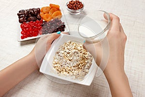 The girl took milk to pour it into oatmeal. Useful and healthy breakfast. light background