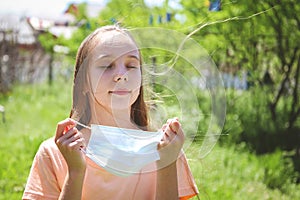 Girl took off her medical face mask. Breathes fresh air outside.  Coronavirus quarantine finish.