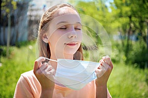 Girl took off her medical face mask. Breathes fresh air outside.  Coronavirus quarantine finish