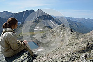 Girl on the top of a cliff, looking over the valley and lake