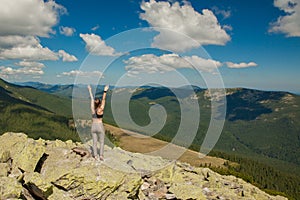 The girl at the top of the mountain raised her hands up. Wide summer mountain view at sunrise and distant mountain range covered.