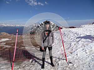 Girl on the top of the mountain, snowy peaks and blue sky