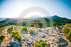 Girl at the top of the mountain. A woman with a backpack is standing on a rock. Climb to the top. Travel to picturesque places.