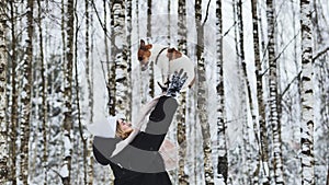A girl tosses up her Jack Russell Terrier dog in the woods in winter. photo