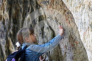 Girl touch a granite rock outdoors