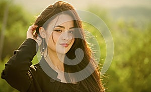 Girl touch long brunette hair on natural landscape photo