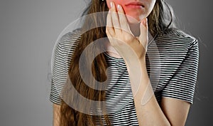 The girl touched a hand over the aching tooth. Toothache. Closeup. The lesion is highlighted in red