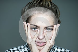 Girl touching her face with long delicate fingers. Portrait closeup of beauty woman with big green eyes and lush