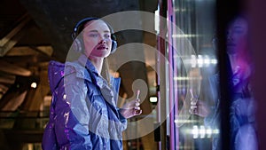 Girl touching snack automat making choice standing in night city subway close up