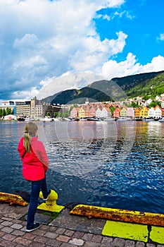 Girl tourist on the background of the sea bay and old wooden houses on the embankment of Bergen