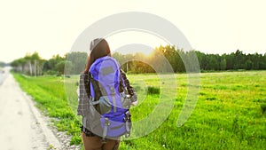 Girl tourist with backpack walking along the road, hitchhiking trip