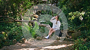 Girl tourist drink water sitting beautiful forest. Woman quenching thirst nature