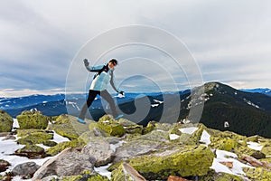 Girl-tourist expresses positive emotions on top of a snowy mountain