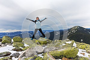 Girl-tourist expresses positive emotions on top of a snowy mountain