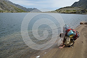 Girl tourist leaves on the sand near the mountain lake