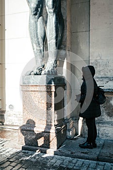 Girl tourist at marble statues of Atlant`s hold ceiling of New Hermitage, St. Petersburg, Russia