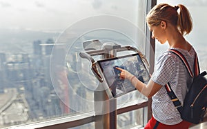 Girl tourist with monitor of computer at window of skyscraper