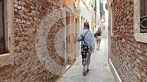 Girl tourist is on a narrow ancient street in Venice, Italy. Traveler walks in Venice.