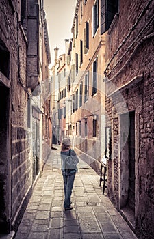 Girl tourist is on a narrow street in Venice, Italy