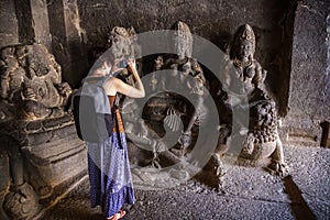 Girl tourist shooting a photo on a smartphone. While walking in a Kailash Temple in Ellora. India