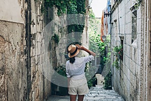 Girl tourist walking through ancient narrow streets on a beautiful summer day in Korcula, Croatia