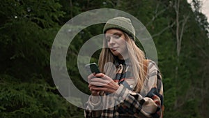 Girl tourist walking in forest and using smartphone gps