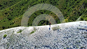 Girl tourist walks in the mountains. Girl on top of the hill looks at the river