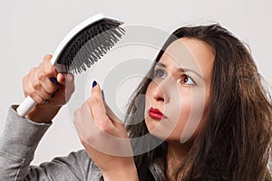 A girl with tousled shaggy hair holds a comb in her hands