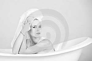 Girl with towel turban sitting in white bathtub