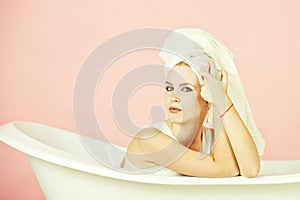 Girl with towel turban sitting in white bathtub