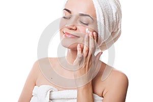 Girl in towels applying cream on her face after bath