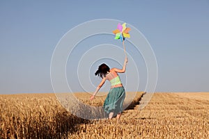 Girl with toy wind turbine at field