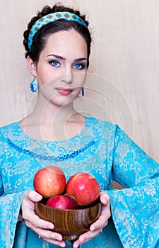 A girl in a traditional blue dress with apples. russian folk costume