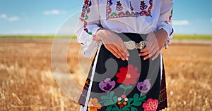 Girl in traditional ethnic folklore costume with Bulgarian embroidery,belt buckle standing on wheat field