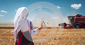 Girl in traditional ethnic folklore costume with Bulgarian embroidery standing on a harvest golden wheat field