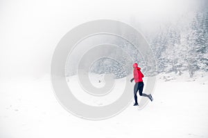 Girl trail running on snow in winter mountains