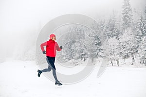 Girl trail running on snow in winter mountains