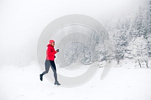 Girl trail running on snow in winter mountains