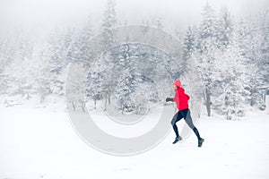 Girl trail running on snow in winter mountains, Poland